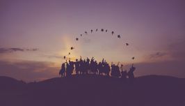  sunset with graduates throwing cap in the air